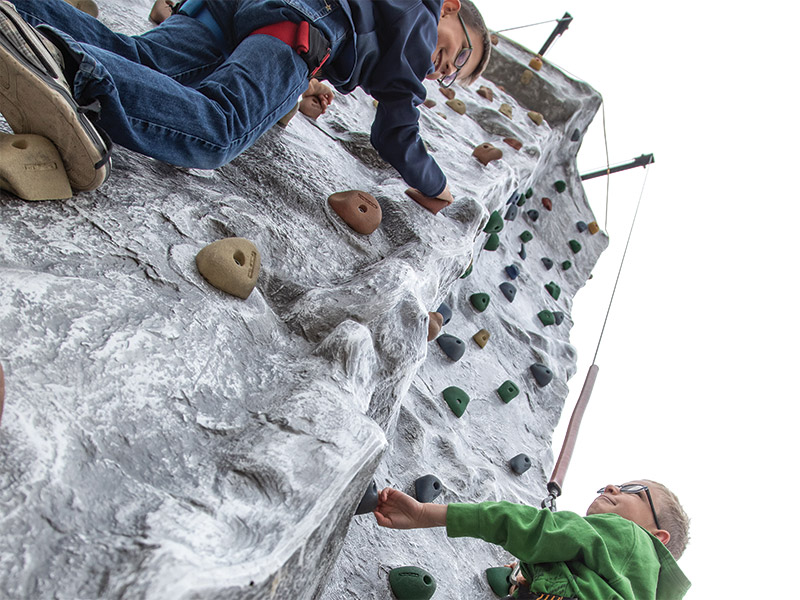 Two kids climbing up the rock wall at Albert's Bistro & Mini Golf, Brandon, Manitoba