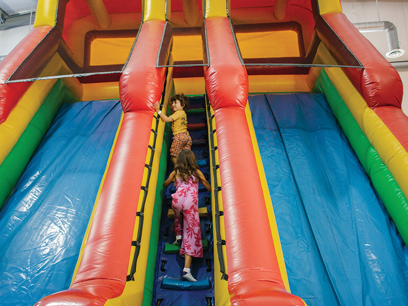 Two children playing on the inflatable slides at Just 4 Kidz, Brandon, Manitoba