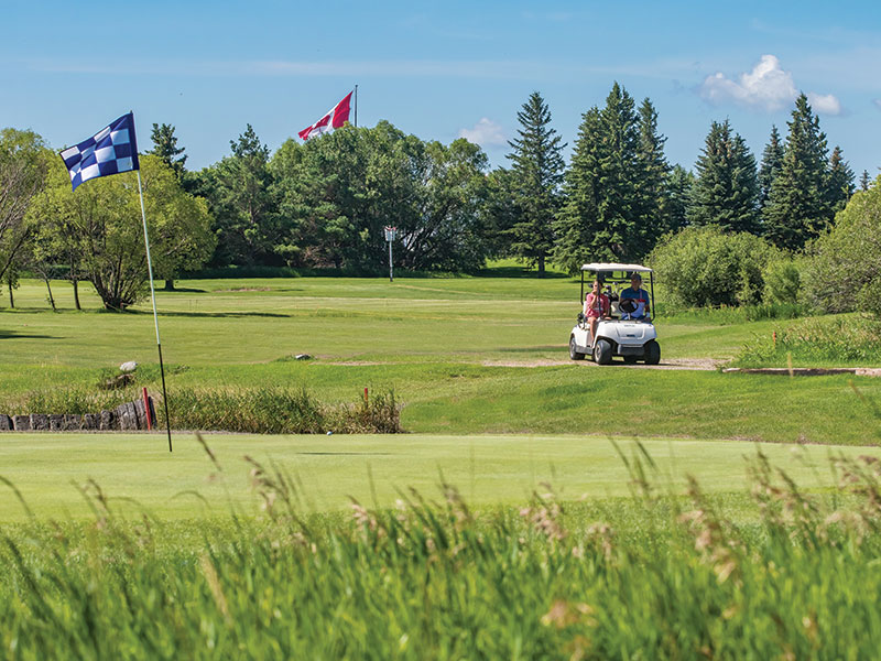 Golfers using a golf cart on the course at Deer Ridge Golf Course, Brandon, Manitoba