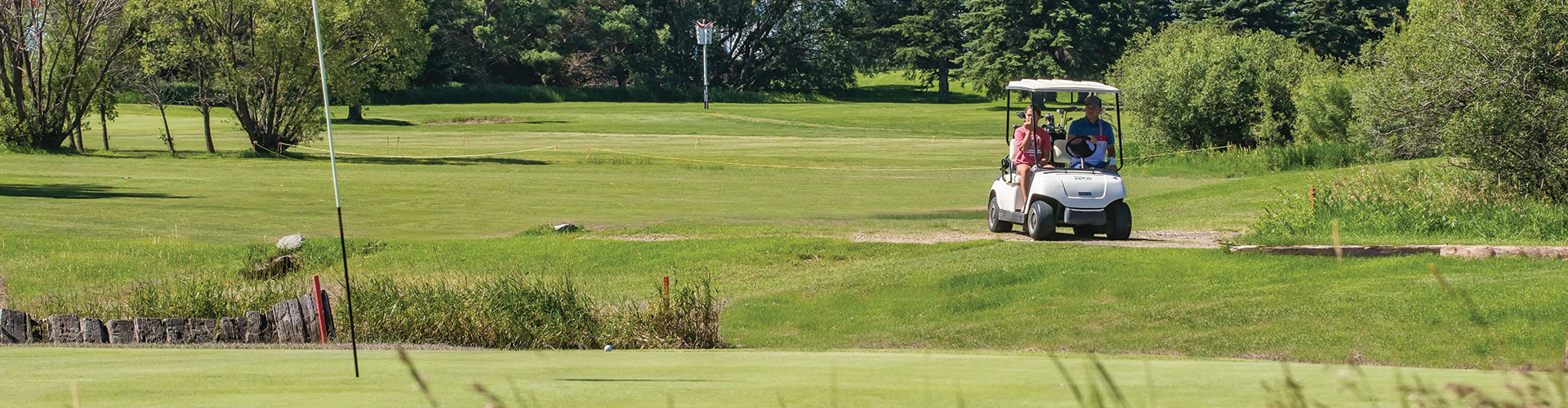 Golfers using a golf cart on the course at Deer Ridge Golf Course, Brandon, Manitoba