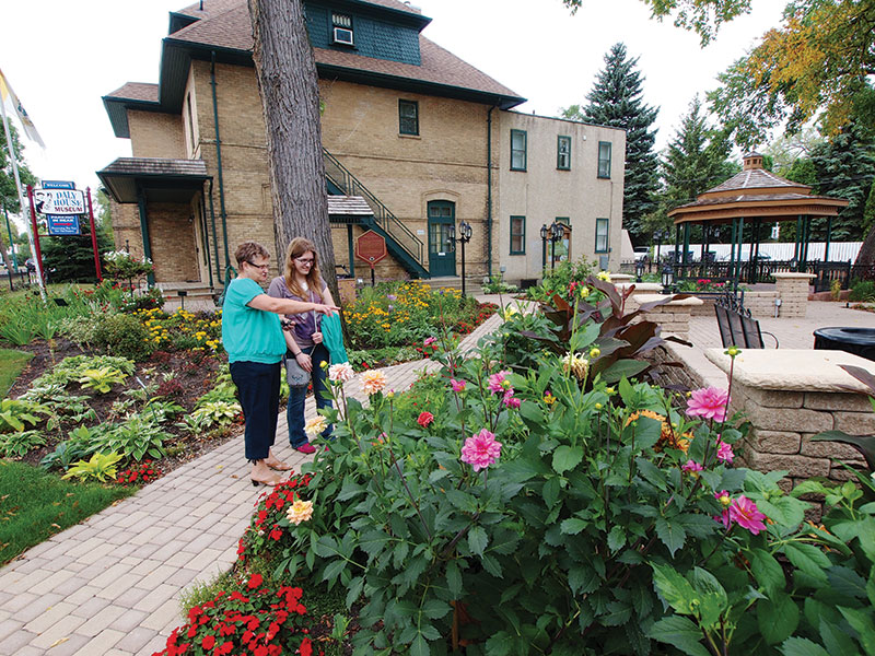 Two women view the flowers in the Victorian Garden at Daly House Museum, Brandon, Manitoba