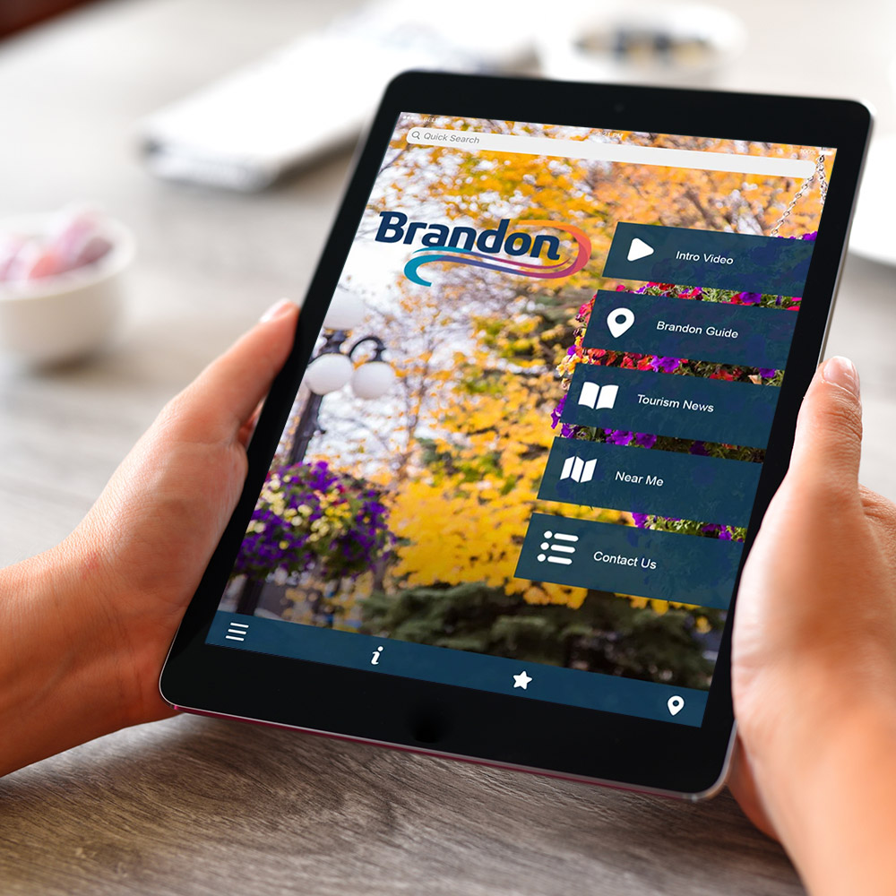 A personal holding a tablet that is displaying the Brandon Tourism app