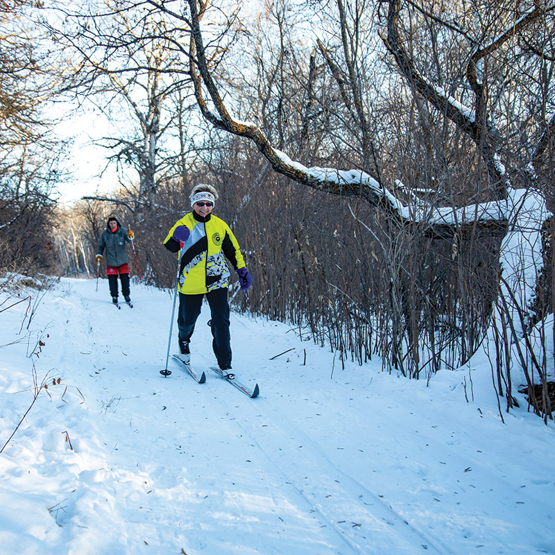 Two people cross-country skiing on a trail in the Brandon Hills