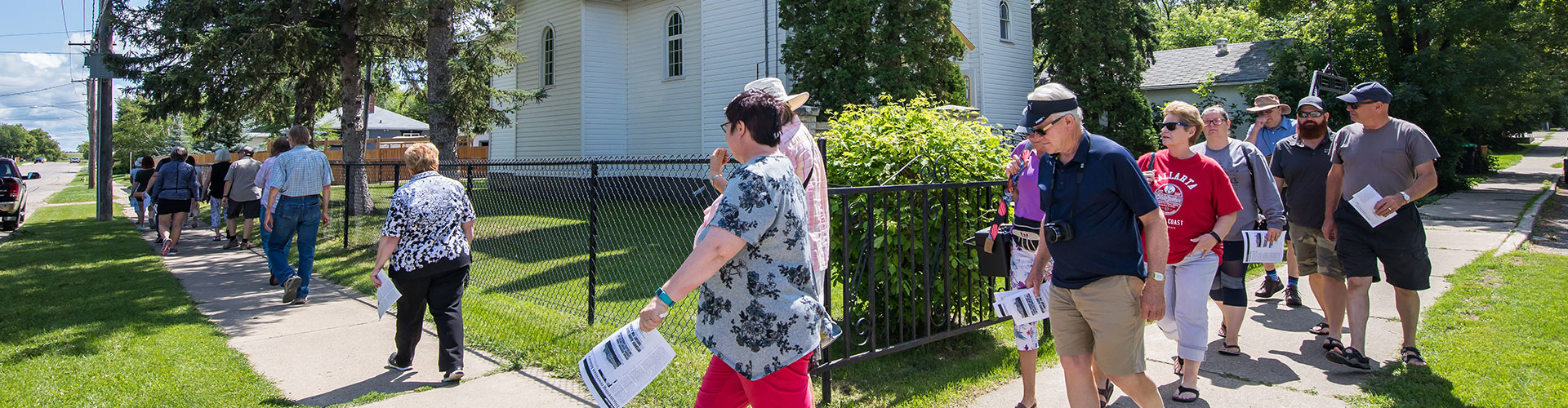 A groups walks past a church as part of the Open Doors Brandon tour held each summer in Brandon, Manitoba